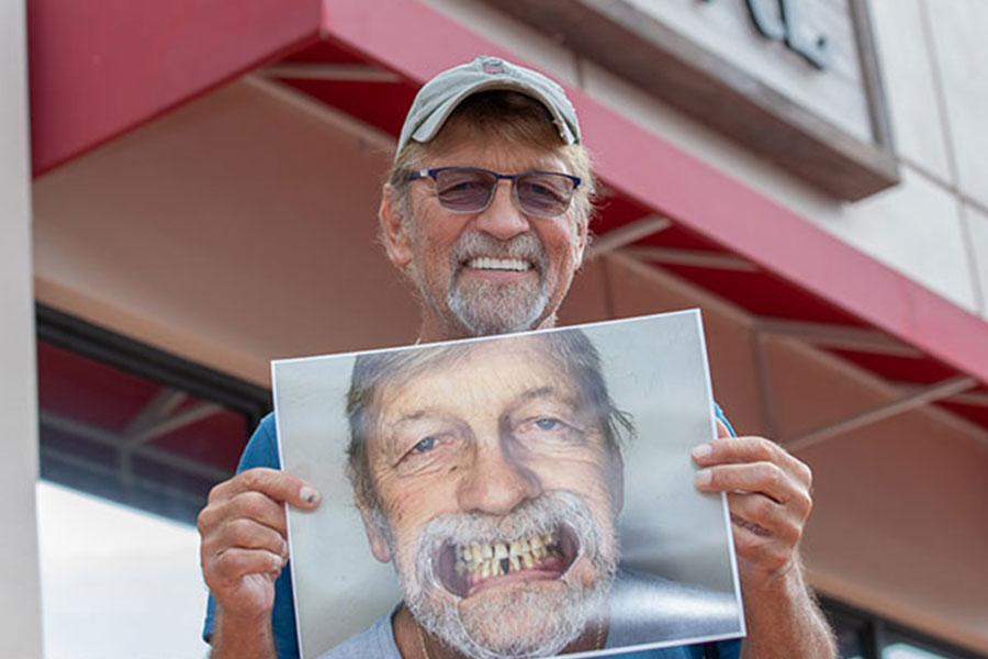 Carl, a full mouth dental implant patient holding his before and after photo at Marsh Cove Dental Center